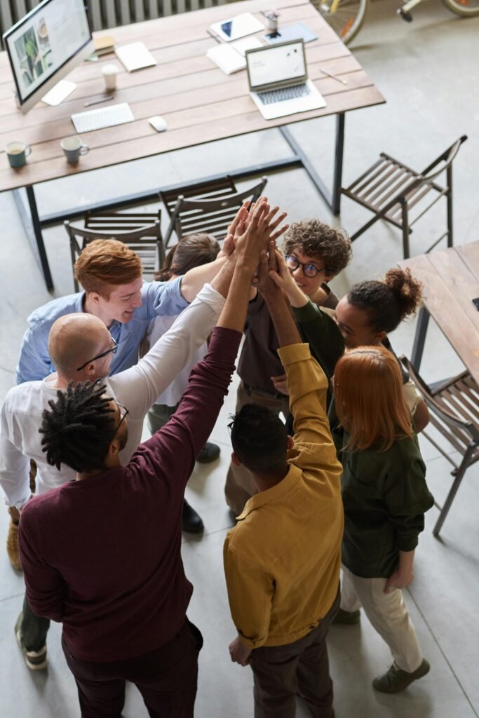 Team alignment A diverse group of professionals high-fiving in a modern office, showcasing teamwork and collaboration.